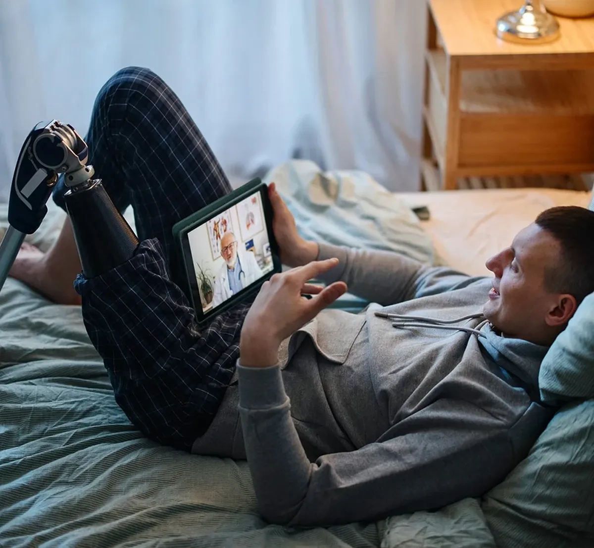 Man with disability lying in bed for his online recovery coaching session4