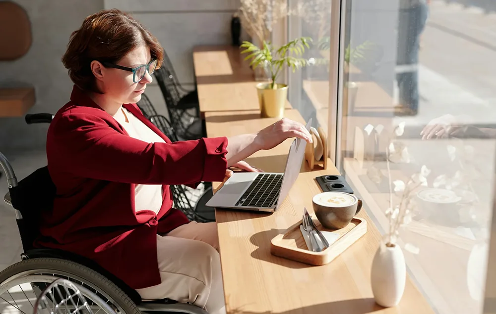 Woman in a wheerchair, in a cafe for her online Support Coordination session