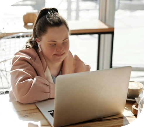 A woman with Down syndrome having an online support coordination meeting on her laptop.