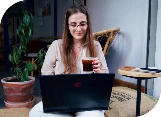 A woman working on her laptop while enjoying a cup of coffee.