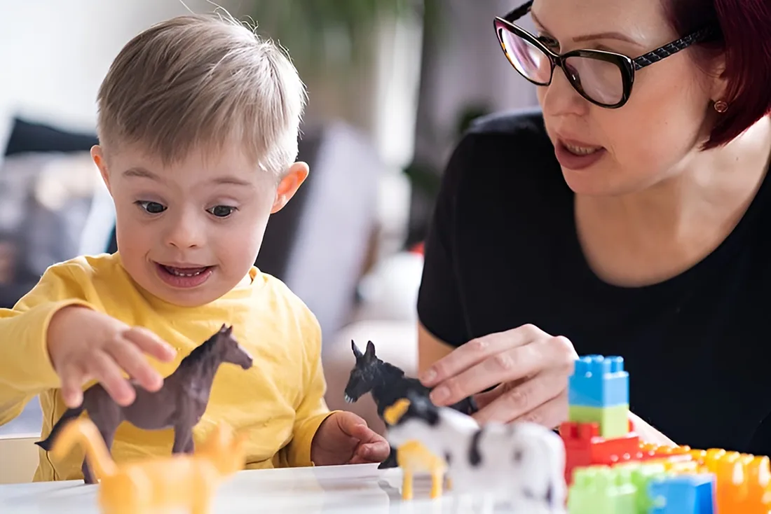 Child with Down syndrome engaging in play therapy with a mother, showing occupational therapy in action.