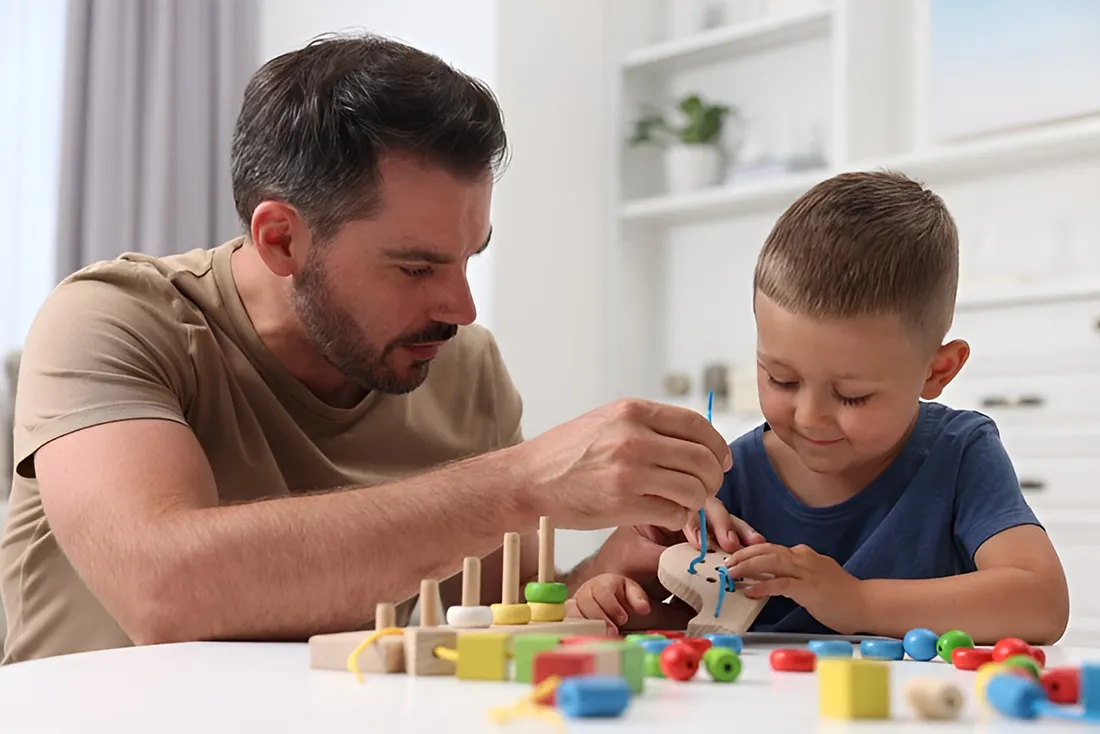 Father and son working on a fine motor skills activity during an occupational therapy session, focusing on child development.