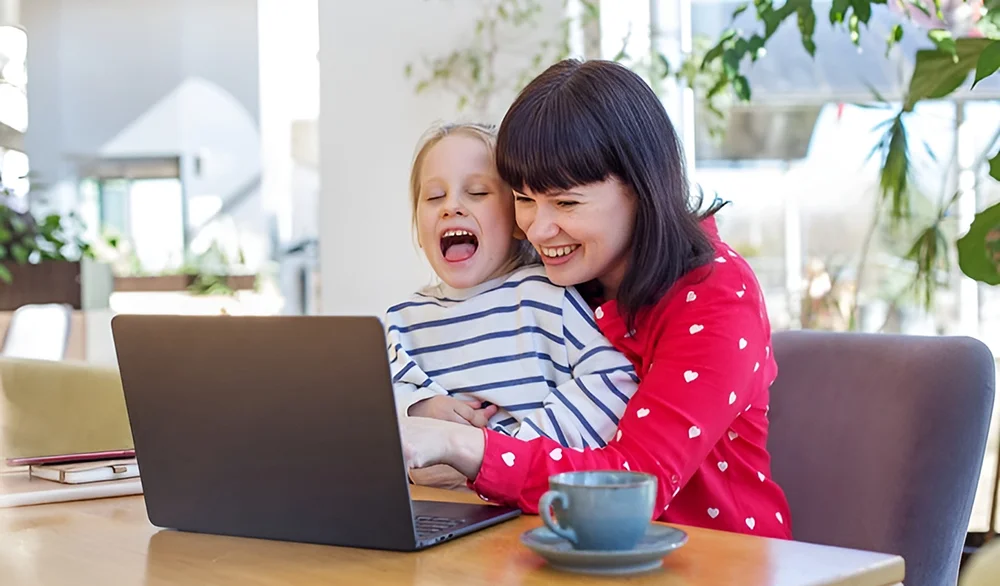 Mother and daughter smiling during an online occupational therapy session, highlighting virtual therapy options for kids.