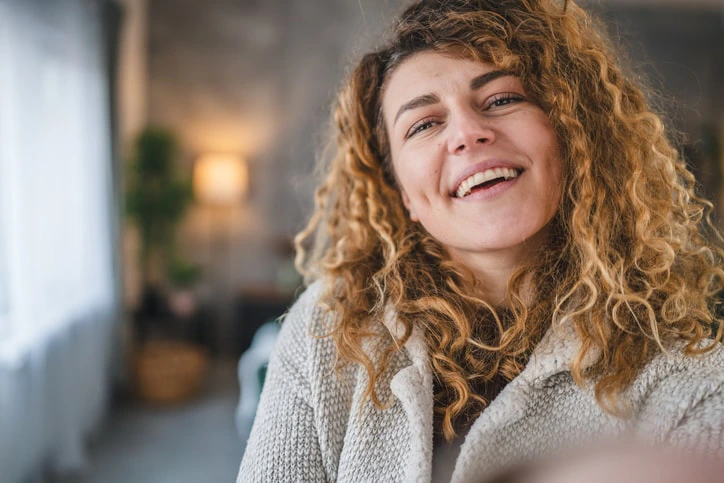 A happy young woman with autism smiling at home, reflecting the positive impact of occupational therapy in improving quality of life and daily independence.