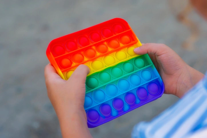 Close-up of hands holding a colourful pop-it fidget toy, commonly used in ADHD therapy for sensory support and focus.