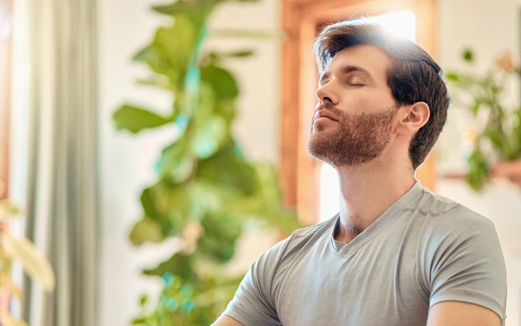 Man practicing mindfulness meditation indoors, a technique often used in ADHD therapy to improve focus and emotional regulation.